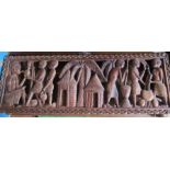 A carved wooden tribal panel, decorated with figures, signed MK Kazembe, 12.5ins x 35.25ins