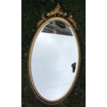 An oval gilt framed wall, with scroll decoration, overall height 26.5ins
