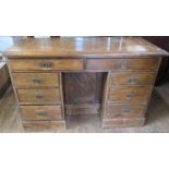 An Antique pine desk, fitted with a cupboard to the kneehole and an arrangement of nine drawers,