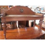 A 19th century oak window seat, the arched back carved with a coat of arms, raised on turned legs,