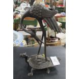 A Japanese Bronze model of a stork, standing on a mythical creature