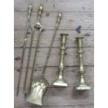 A pair of brass candlesticks, height 14ins, together with a three pieces brass fire tool set