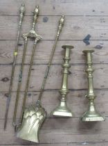 A pair of brass candlesticks, height 14ins, together with a three pieces brass fire tool set