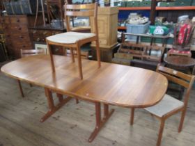 A mid century teak extending dining table, with 2 extra leaves, together with a set of four dining