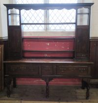 An Antique dark oak dresser, the open back with shelves and cupboards, the base fitted with drawers,