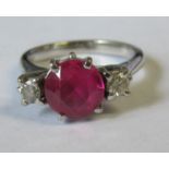 A ruby and diamond ring, set in white metal, the central round cut ruby, possibly a synthetic