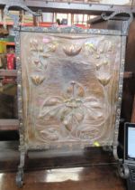 An Arts and Crafts copper and metal fire guard, the copper panel with embossed lily and pad