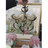 An Art Nouveau brass hanging light fitting, with three cranberry and frosted glass frilly shades