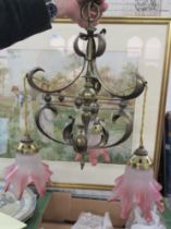 An Art Nouveau brass hanging light fitting, with three cranberry and frosted glass frilly shades