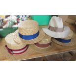 Four straw boaters, a grey top hat and another hat