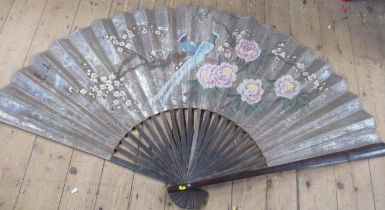 A large Eastern design fan, decorated with foliage and prunus, together with a smaller example