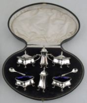 A cased six piece condiment set, comprising a pair of open salts with blue glass liners, a pair of