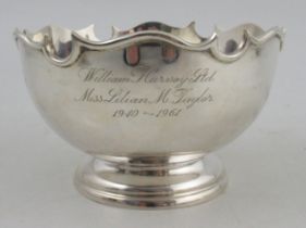 A silver circular bowl, with shaped edge, presentation inscription, raised on a circular foot,