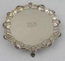 A Georgian silver card tray, with ogee and shell border, engraved with initials, raised on three