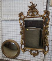 A gilt framed wall mirror, with scroll and flower head decoration, together with a circular wall