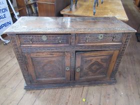 An Antique Oak cabinet fitted two drawers over two cupboard doors having carved decoration all over,