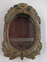 A small wall mirror, with oval plate and carved frame, overall dimensions 11ins x 7ins