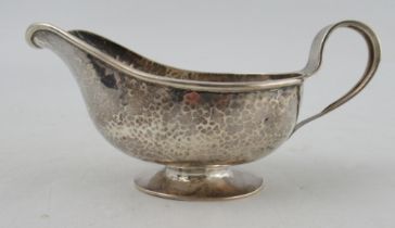 A George V Arts and Crafts silver sauce boat, with hammered decoration and loop handle, Birmingham