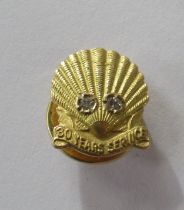 A 9ct yellow gold shell stud, given for 30 years service, set with two eight cut diamonds each