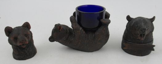 Two carved Black Forest bear inkwells, together with a carved Black Forest bear lying on its back