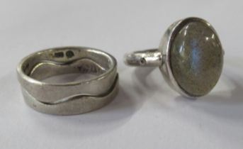 A silver coloured stacking ring, in two sections, together with a stone set ring