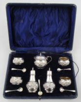 A cased seven piece condiment set, with embossed decoration, comprising four open salts with gilt