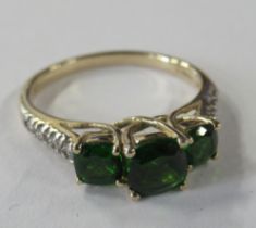 A 9ct gold three stone ring, set with three green garnets, and four diamonds to the shoulders