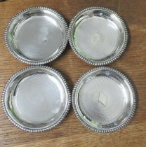 A set of four silver circular dishes, embossed with the different suits, weight 7oz