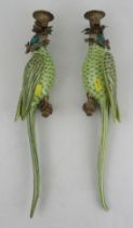 A pair of wall sconces, modelled as parrots, in green and yellow, with gilt metal candle holder