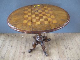 A 19th century walnut games table raised on turned column, terminating in four outswept feet,