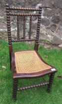 A cane seated chair with bobbin decoration