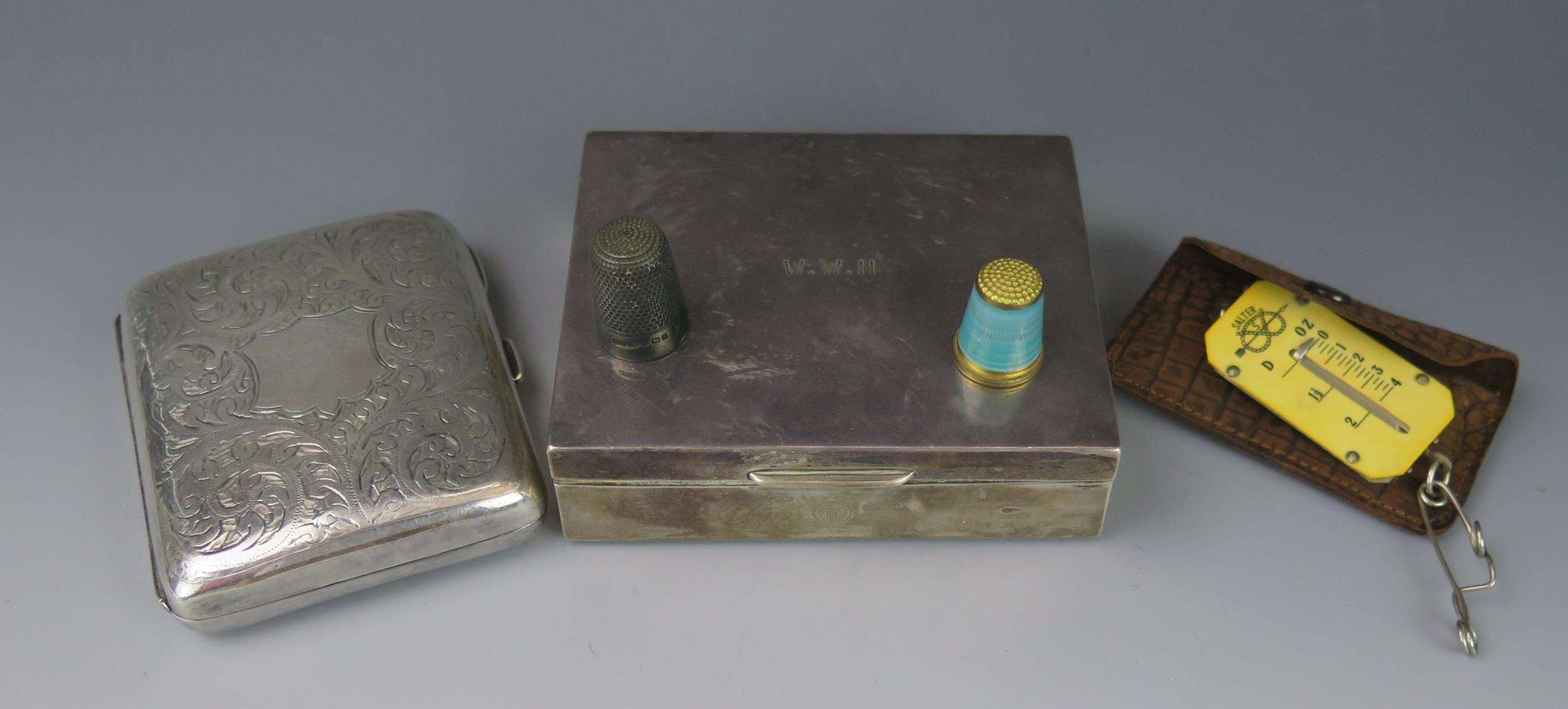 A silver cigarette box, all marks worn, a silver thimble, spring scale and a plated cigarette case.