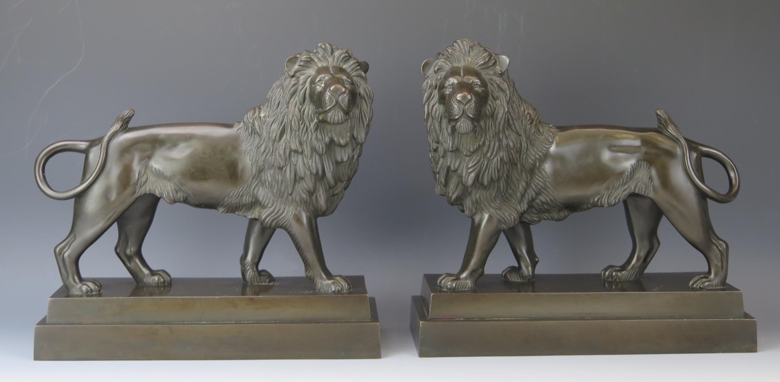 A pair of late 19th/early 20th century bronze lions, raised on all fours with turned heads,