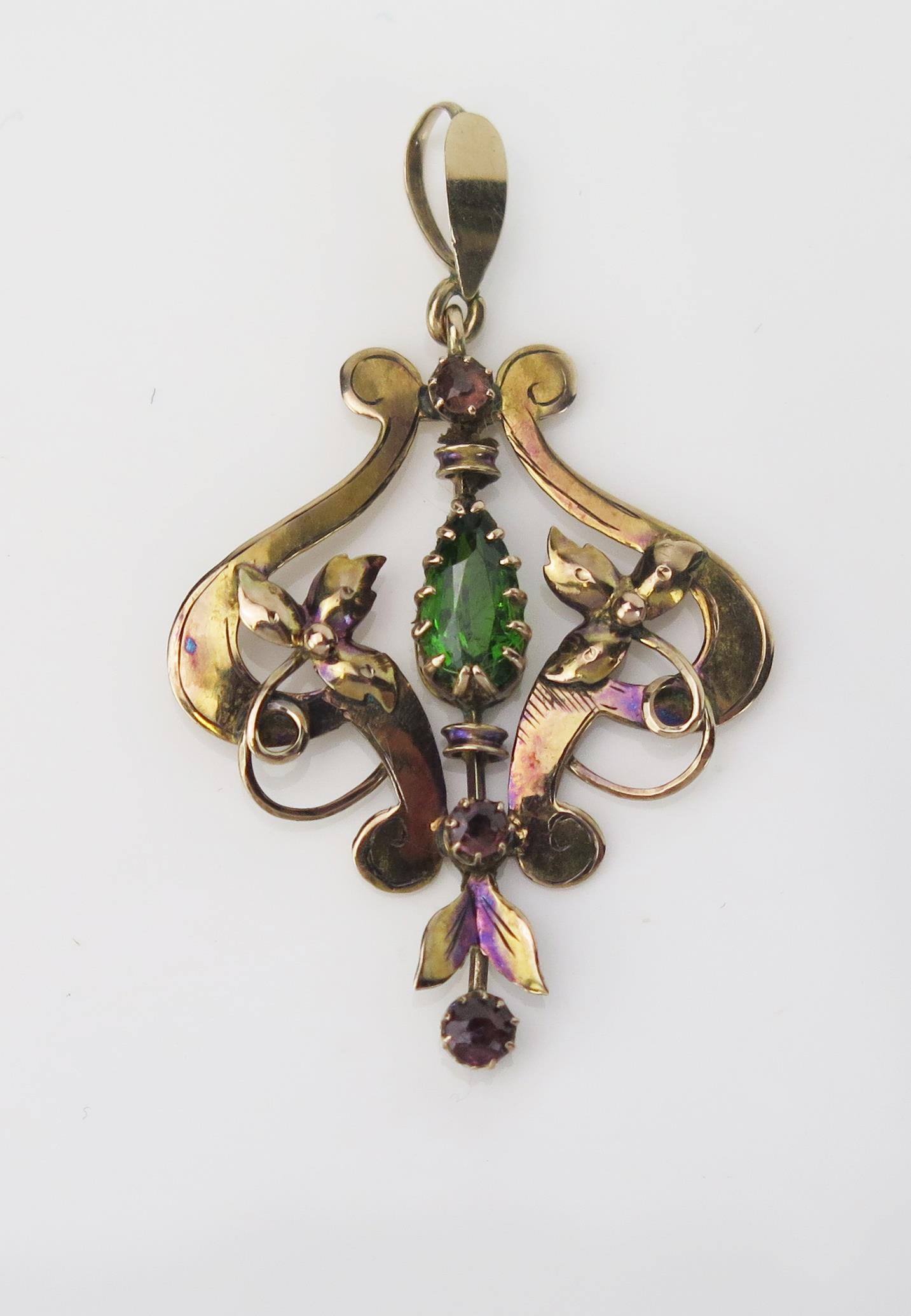 An Art Nouveau 9ct Gold Pendant, the central pear shaped Peridot, above two small