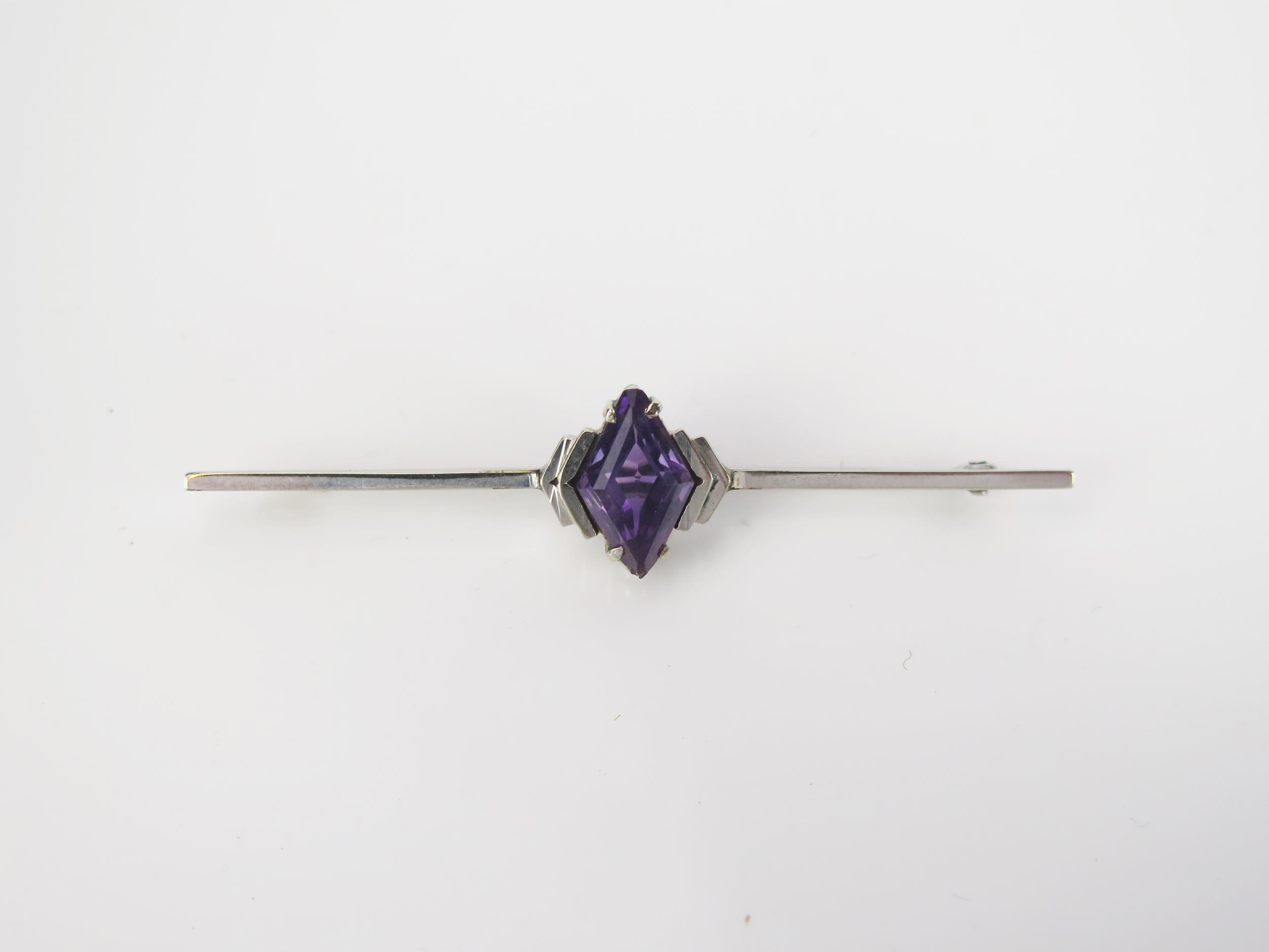 An Art Deco Amethyst 9ct White Gold Bar Brooch, diamond cut stone, stamped 9ct, 5.5cm, 3.2g total.