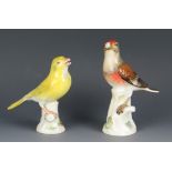 Two Meissen porcelain finches, perched on tree stumps, 13cm and 12 cm high. Both with damaged beaks.