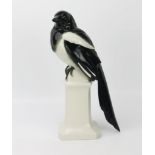 A German porcelain model, of a magpie perched on a bollard, 31cm high.