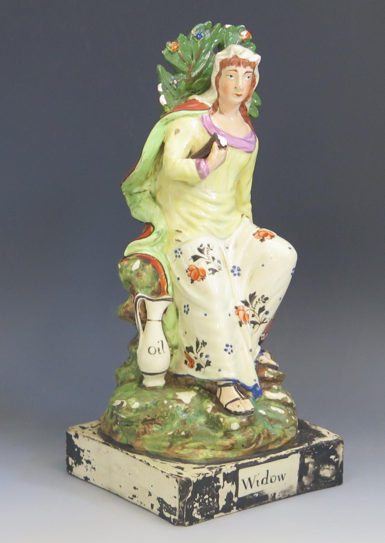 A Staffordshire pottery pearlware figure 'Widow' 26cm high. Chips to the foliage and loss of - Image 2 of 2