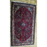 A Persian rug, the wine red field with central floral pole medallion and all over floral sprays