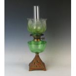 A late Victorian cast iron and green glass oil lamp, with etched glass shade and chimney 54cm high.