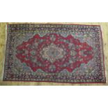 A Persian design rug, the wine red field with central ivory pole medallion and foliate spandrels