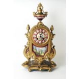 A late 19th century French gilt metal an porcelain mounted mantel clock of arched outline, with
