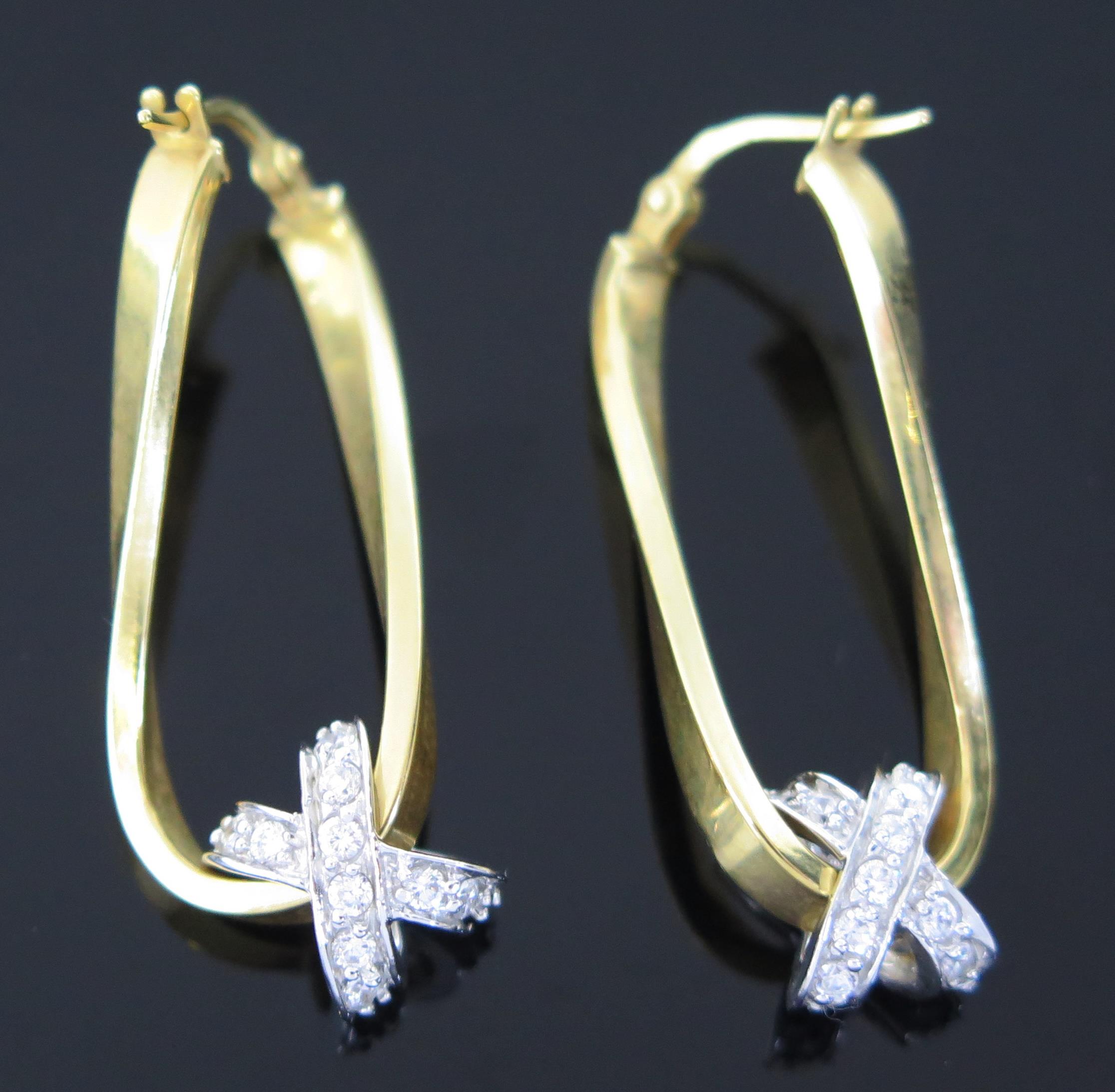 A pair of Modern 9ct Gold earrings with white stone crossed ribbons, 3.4g, (2).