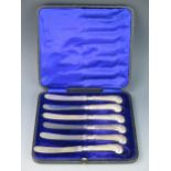 A set of six silver pistol handled butter knives with steel blades contained in a fitted case,