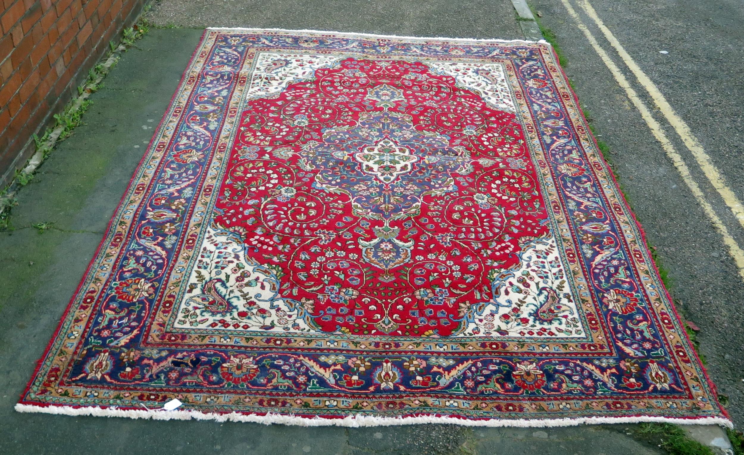 A 20th Century Kashan style wool carpet, blue central medallion, red field, cream spandrels, blue