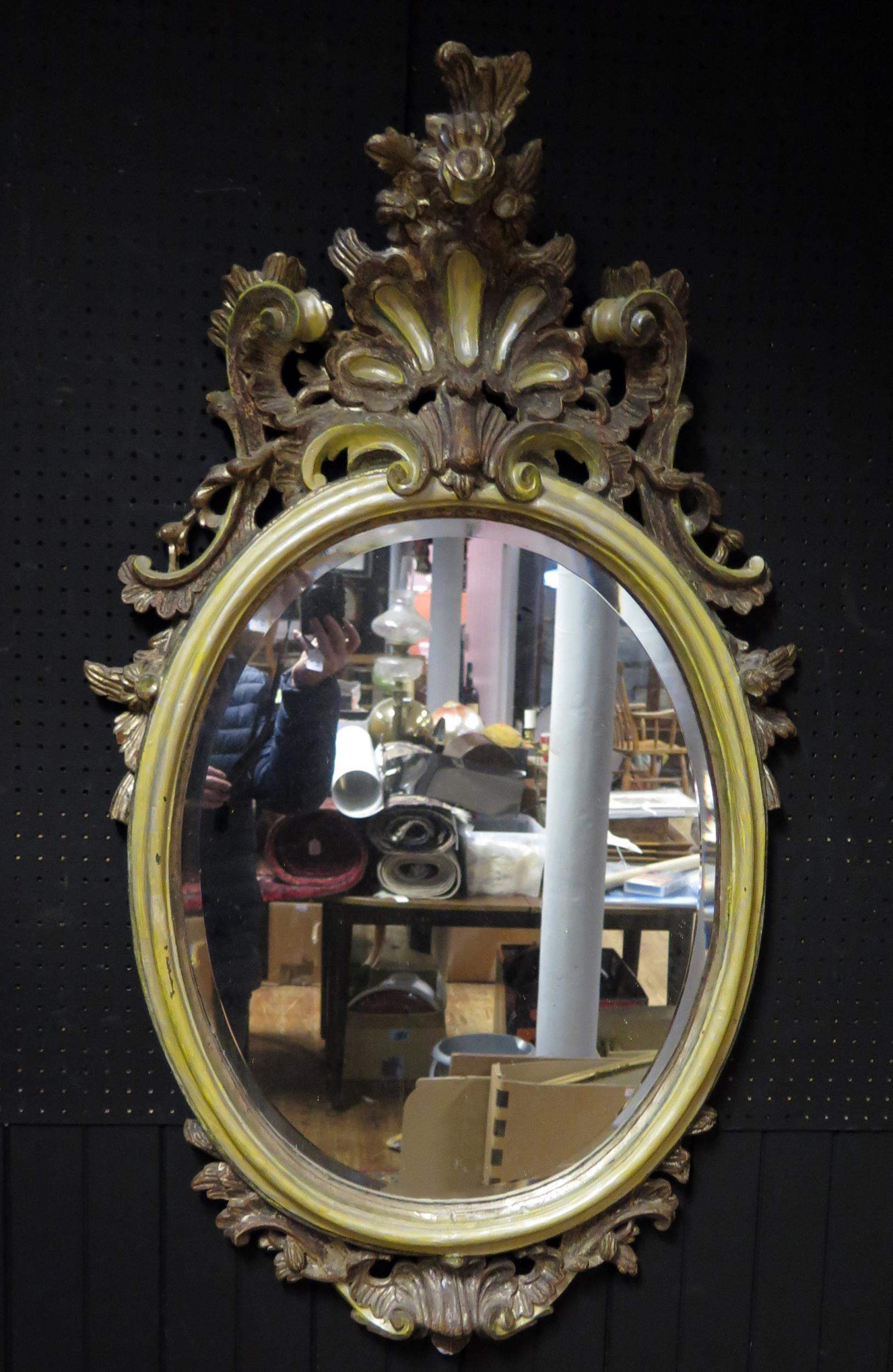 A giltwood and painted oval wall mirror, the bevelled mirror plate enclosed within a cushion frame