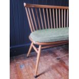 An Ercol love seat, the spindle back with cowhorn top rail, the solid seat with chamfered and wavy