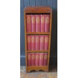 A 1920's oak bookcase containing fifteen volumes of the works of Charles Dickens. 31cm wide
