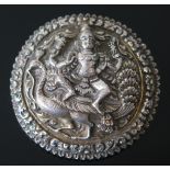 An Indian White Metal Brooch, the embossed decoration of a Hindu figure above a peacock, 53mm diam.,