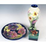 A Moorcroft pottery plate with Clematis pattern decoration, to a cobalt blue ground, 26cm